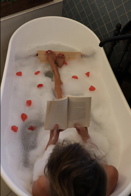 Women reading using bath tub foot rest